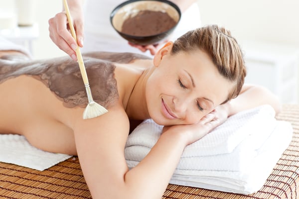 Relaxed woman enjoying a mud skin treatment in a Spa center